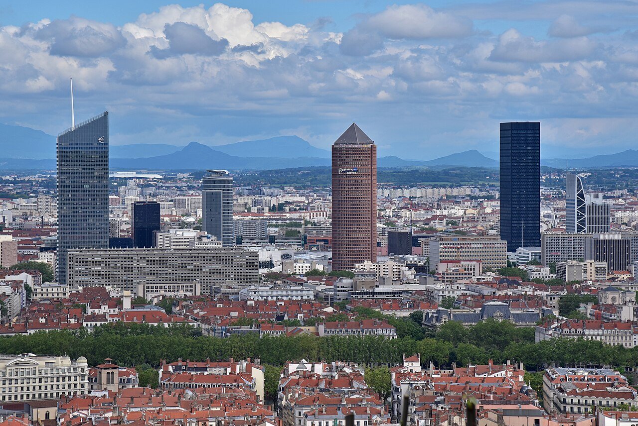 Lyon skyline at sunset showing the Part-Dieu business district towers and the Rhône river with the hills of Fourvière behind