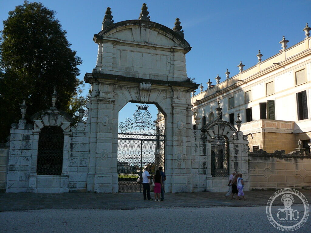 A monumental stone gateway of Villa Pisani at Stra, a wrought-iron gate under its arch and statues along the top of the wall
