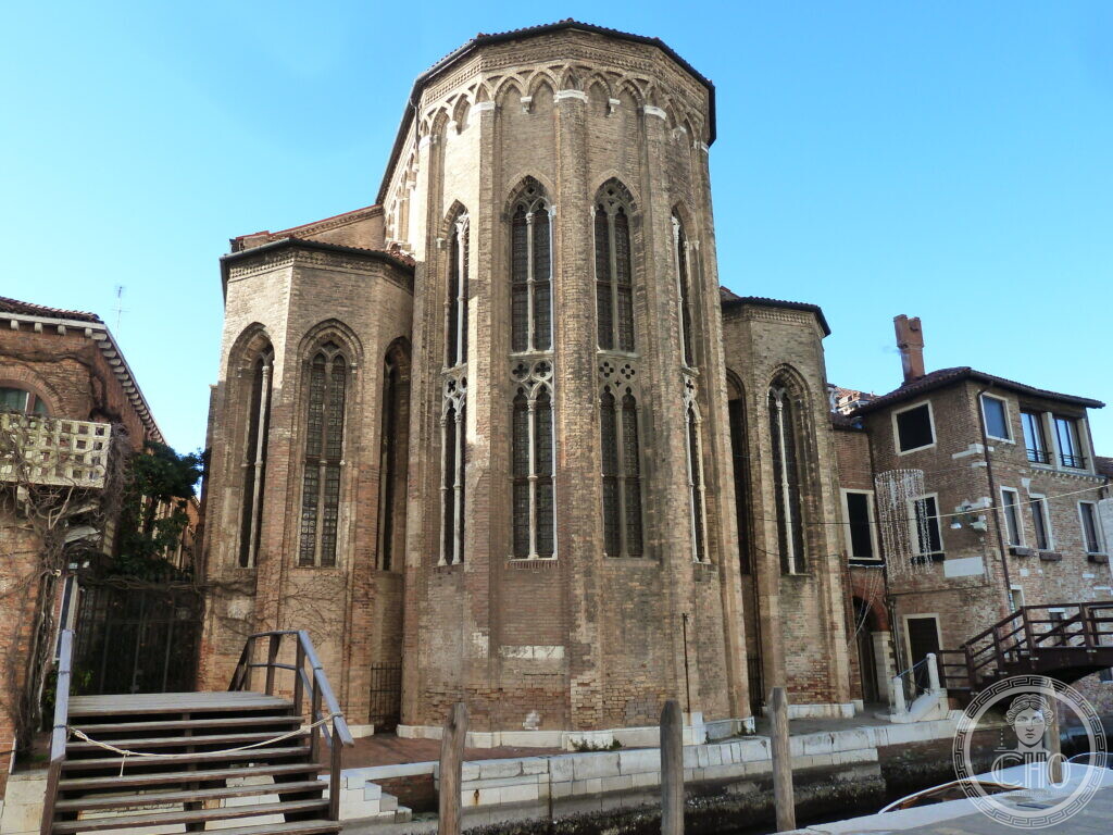 The polygonal brick apse of the former church of San Gregorio in Venice, its tall Gothic lancet windows filled with stone tracery, rising straight out of a small canal