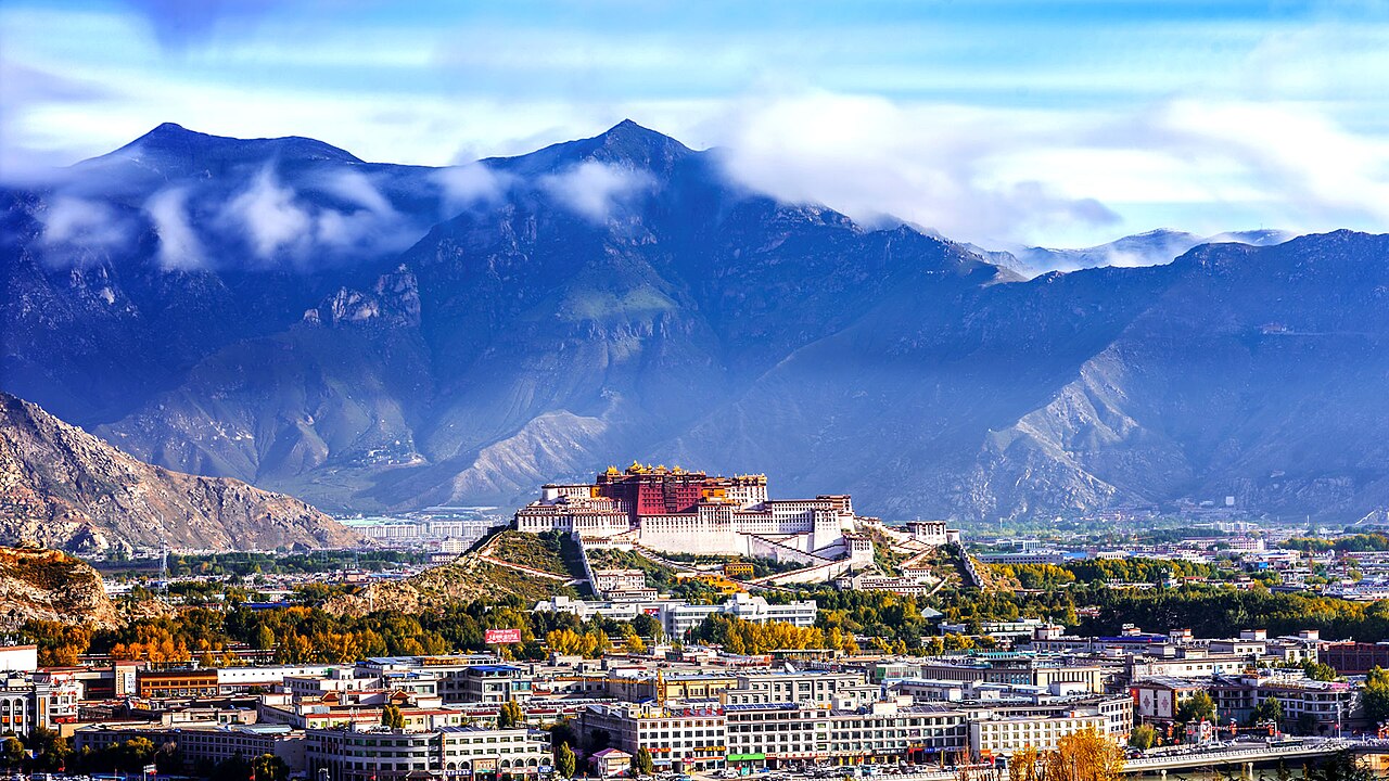 The Potala Palace in Lhasa rising thirteen stories above the Red Hill, its whitewashed lower Potrang Karpo topped by the red Potrang Marpo crown palace against the Tibetan sky