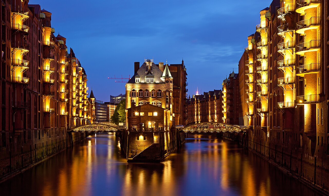 Speicherstadt warehouse district at dusk, Hamburg — red-brick Gothic Revival warehouses reflected in the canals of the free port