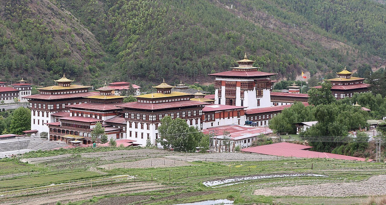 Tashichho Dzong, the fortress-monastery in Thimphu that serves as the seat of the Bhutanese government, with whitewashed walls and golden roofs against mountains