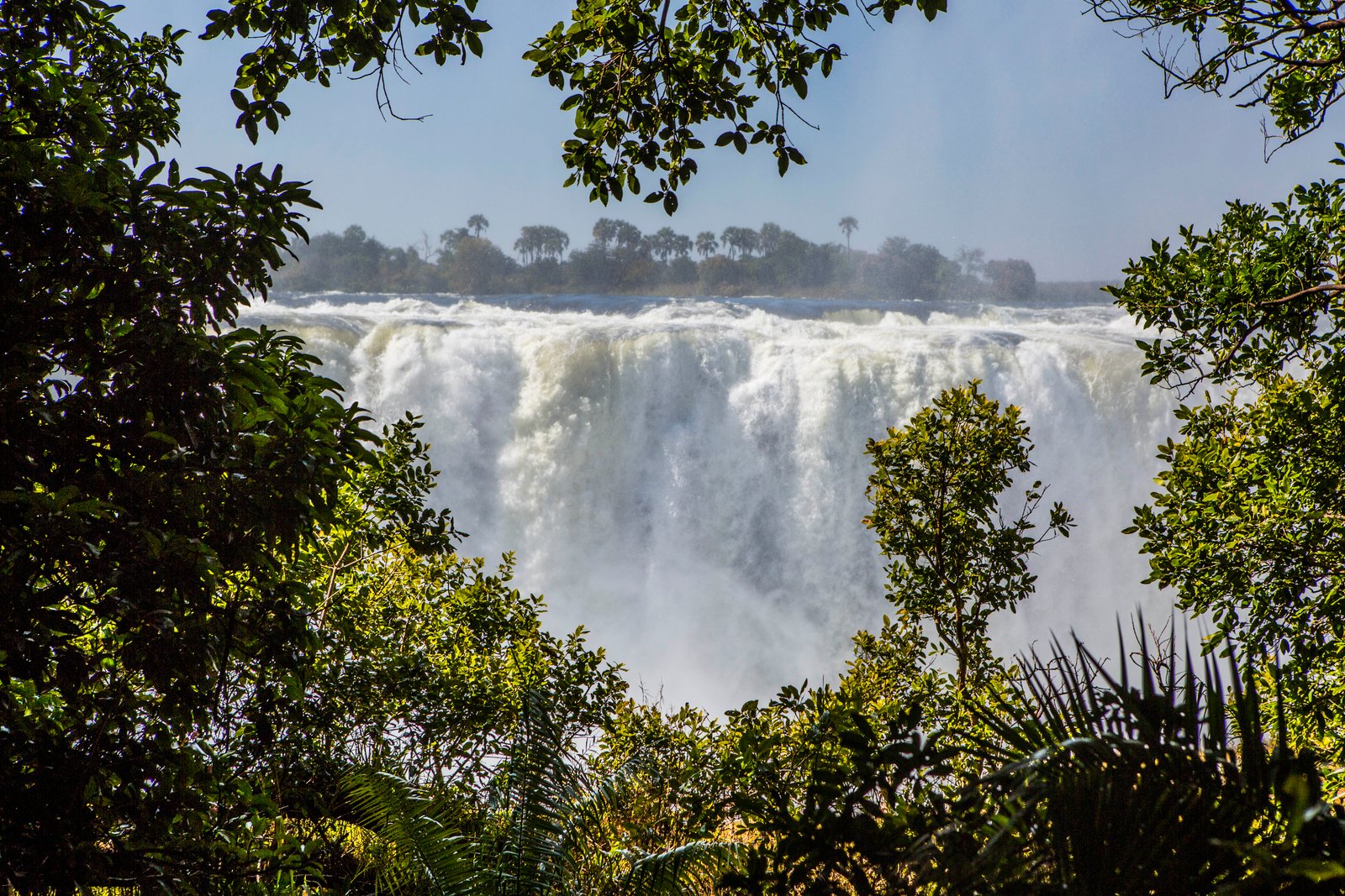 Spray and mist rising above Victoria Falls waterfall seen from the Zimbabwe bank