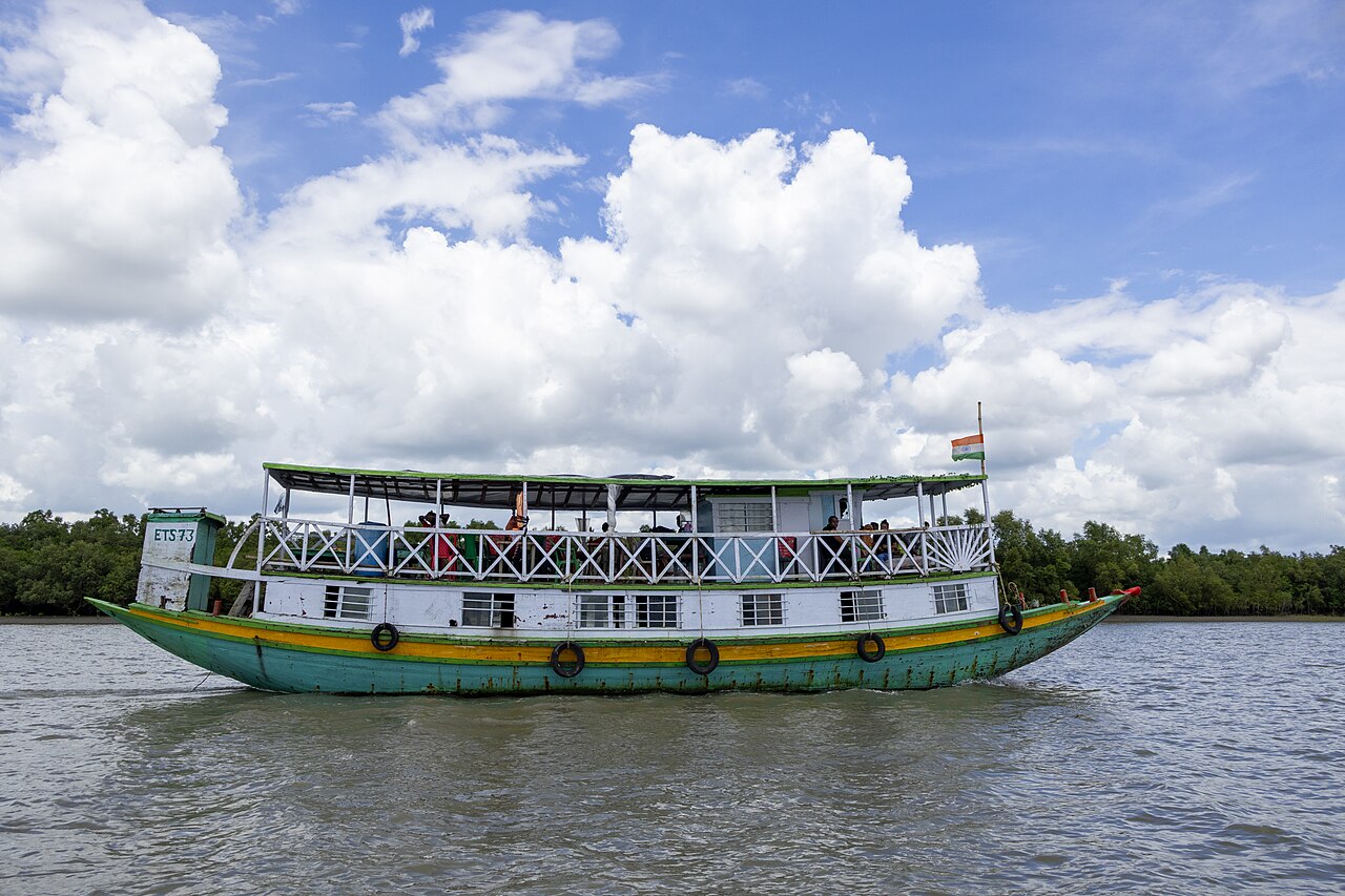 Tourist boat moving through a narrow mangrove waterway in the Sundarbans, West Bengal