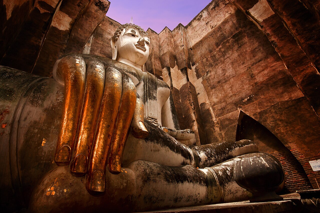 The giant seated Buddha image of Wat Si Chum, Sukhothai Historical Park, Thailand — the Phra Achana, a massive stucco-over-brick seated Buddha image approximately 14.7 metres high, visible through the narrow vertical doorway of the mondop (shrine chapel) at the UNESCO-inscribed Historic Town of Sukhothai, capital of the first independent Thai kingdom (1238–1438 CE)