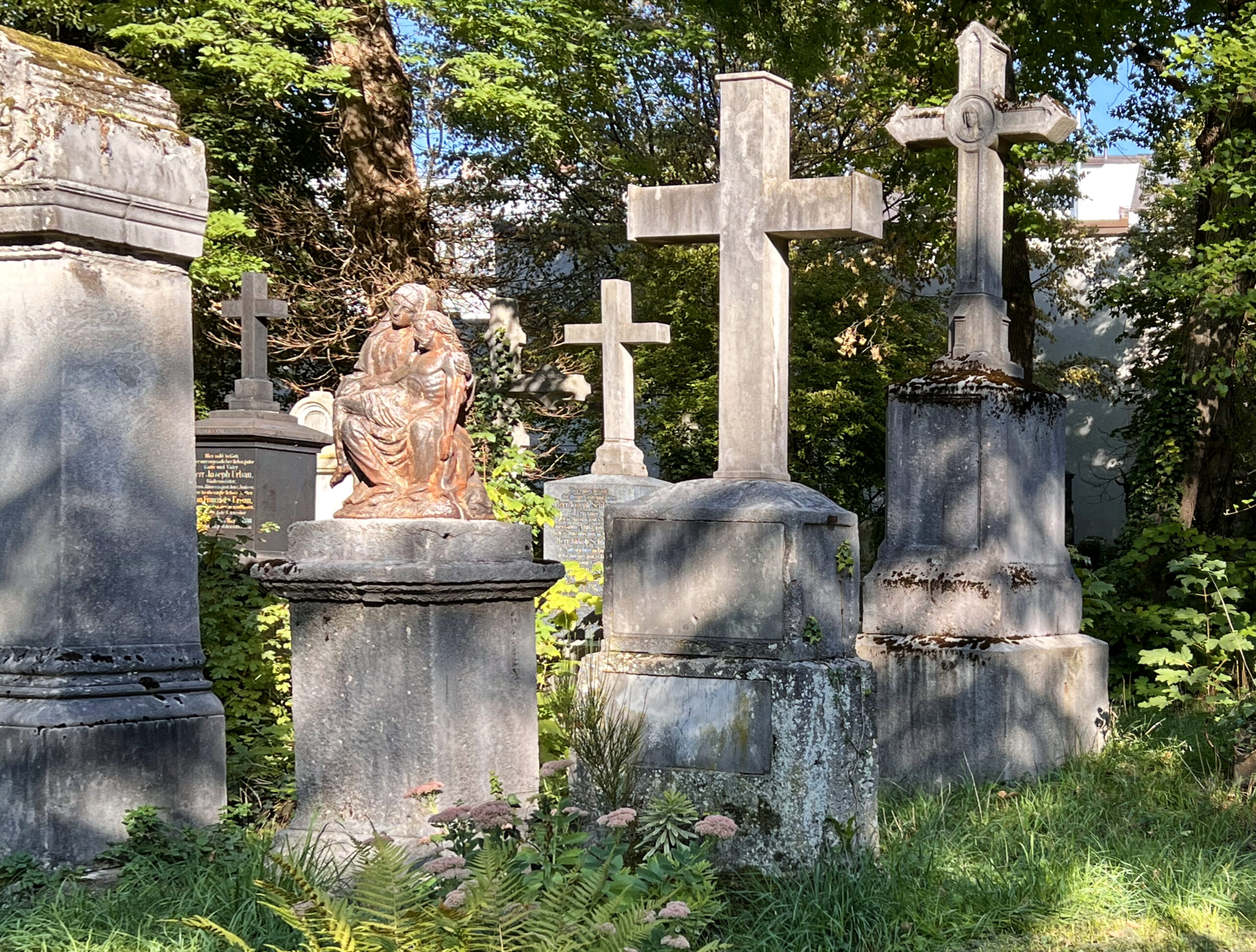 Stone crosses, a weathered Piet&agrave; and tombs overgrown with ivy in the old south cemetery of Munich