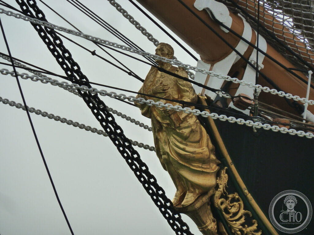The gilded figurehead of Amerigo Vespucci under the bowsprit, among chains and rigging