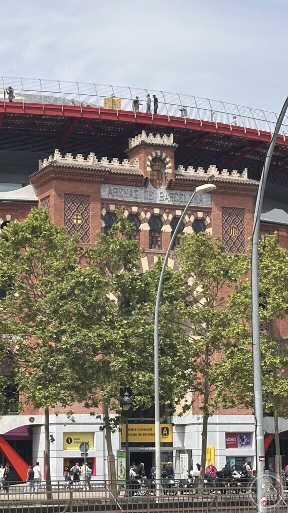 Close-up of the Neo-Mudejar brick facade of Arenas de Barcelona with the 'Arenas de Barcelona' lettering and decorative arcading