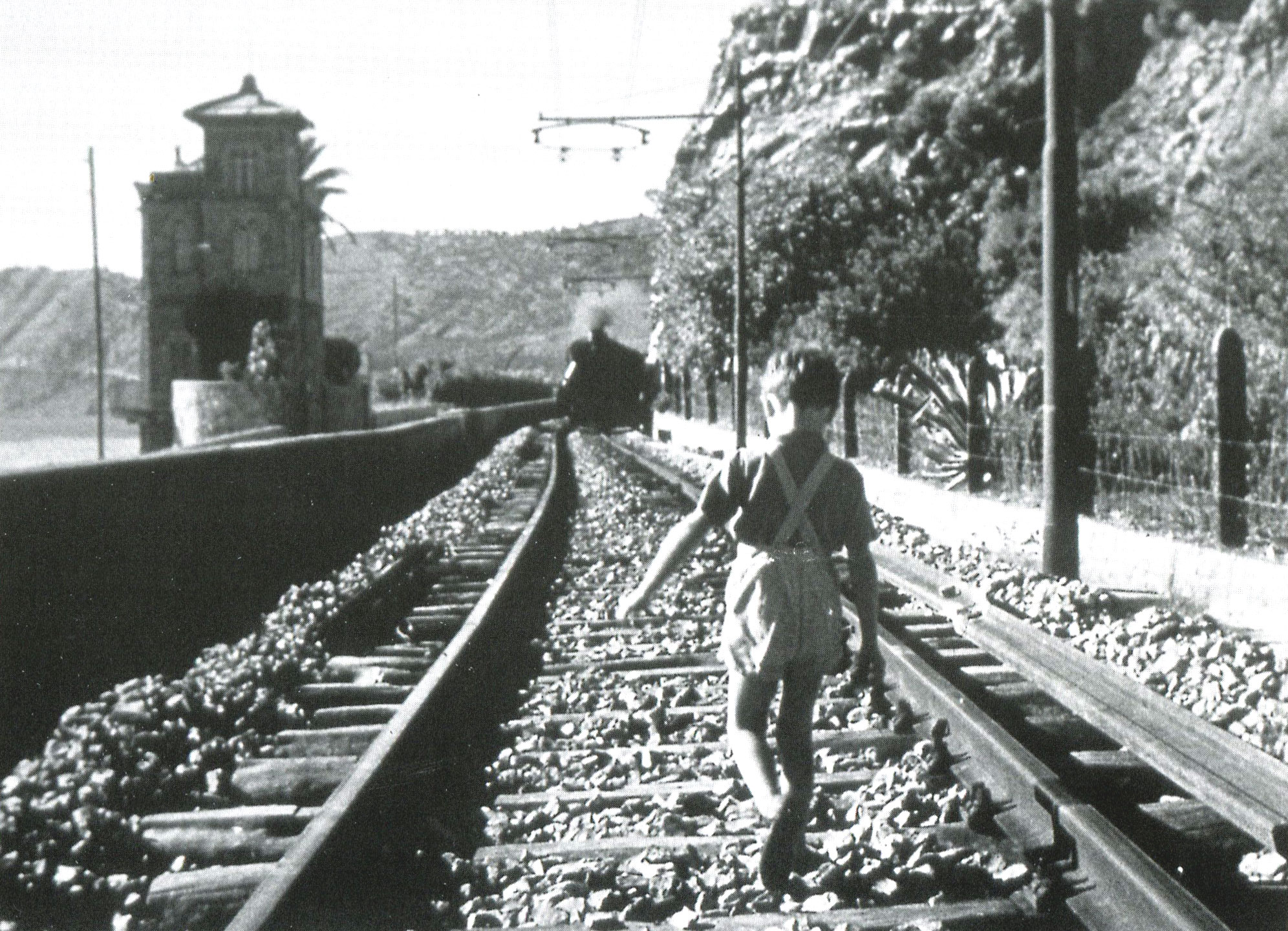 A small boy running along a railway line, a still from the 1943 film I bambini ci guardano