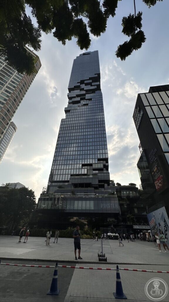 The MahaNakhon tower seen from the plaza below, its glass facade cut by a spiral of recessed blocks