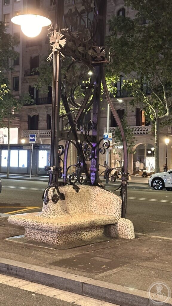 The same bench and lamp at night, lit from above, with the boulevard behind