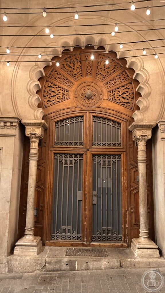 A polylobed arch over a carved wooden fanlight, flanked by slender columns, on a Barcelona street