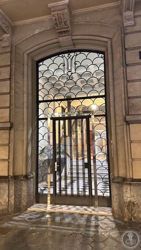 An arched entrance with a fan of iron scrollwork, a keystone carved with initials and the date 1890