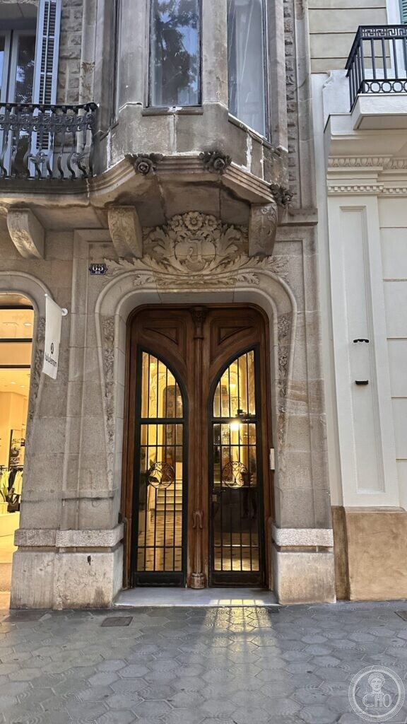A carved stone doorway with a garland over the arch and a bay window resting on brackets above