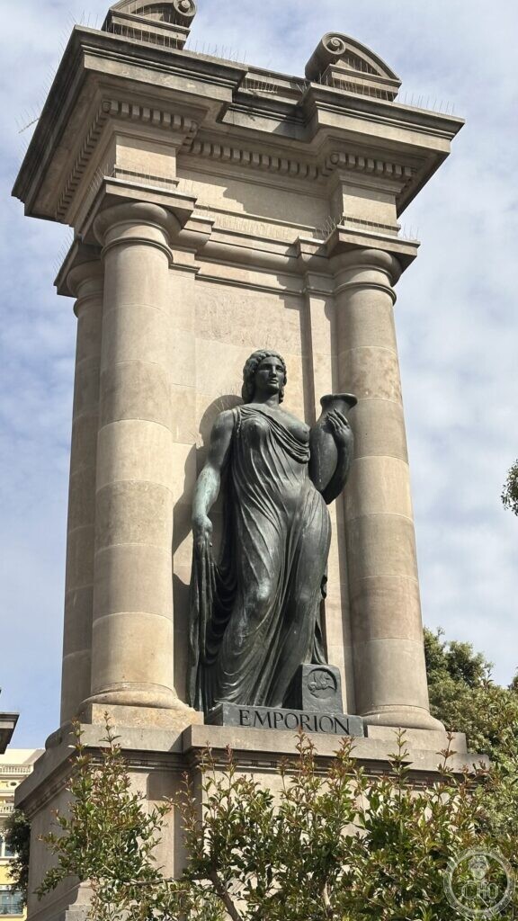 A bronze female figure holding an amphora, standing in a stone niche between columns