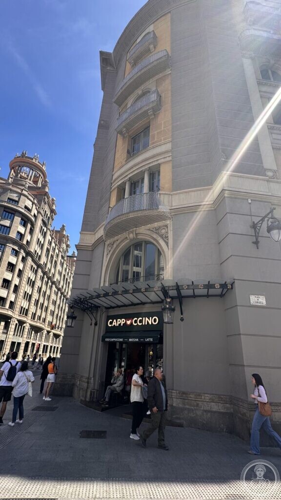 A rounded 1920s corner block on Plaça de l’Àngel with an iron canopy over the ground floor