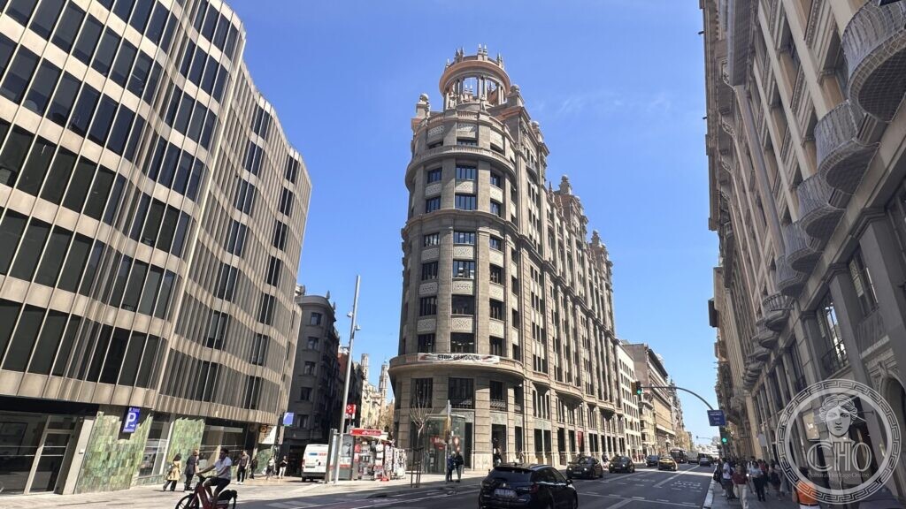 A view along Via Laietana with the corner building on the left and traffic in the street