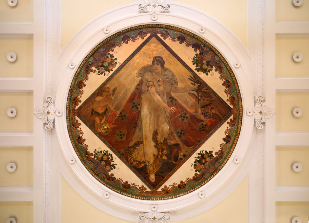 Painted ceiling medallion inside Caffè Gilli, Florence: a woman in a long gown and fur-trimmed cloak between two putti, framed by a garland border in white stucco