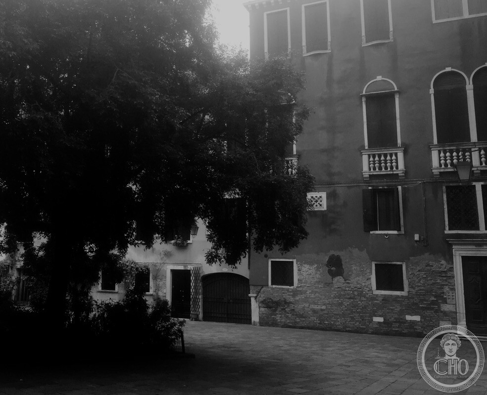 Atmospheric black and white view of Campiello de la Cason in Cannaregio with a large mature tree and Venetian Gothic palazzo facade