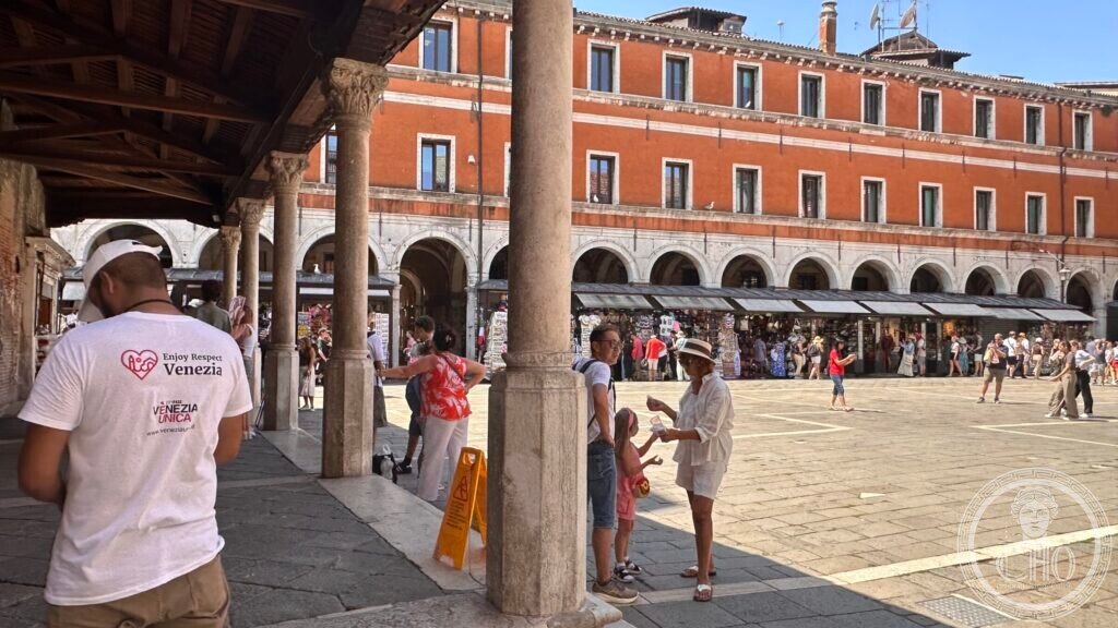 Stone columns of the portico in the foreground, the square and its arcades behind