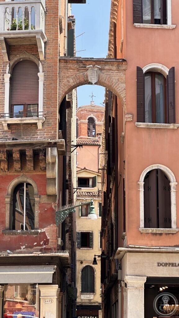 View through a brick archway (sottoportego) near Campo San Luca toward a bell tower beyond