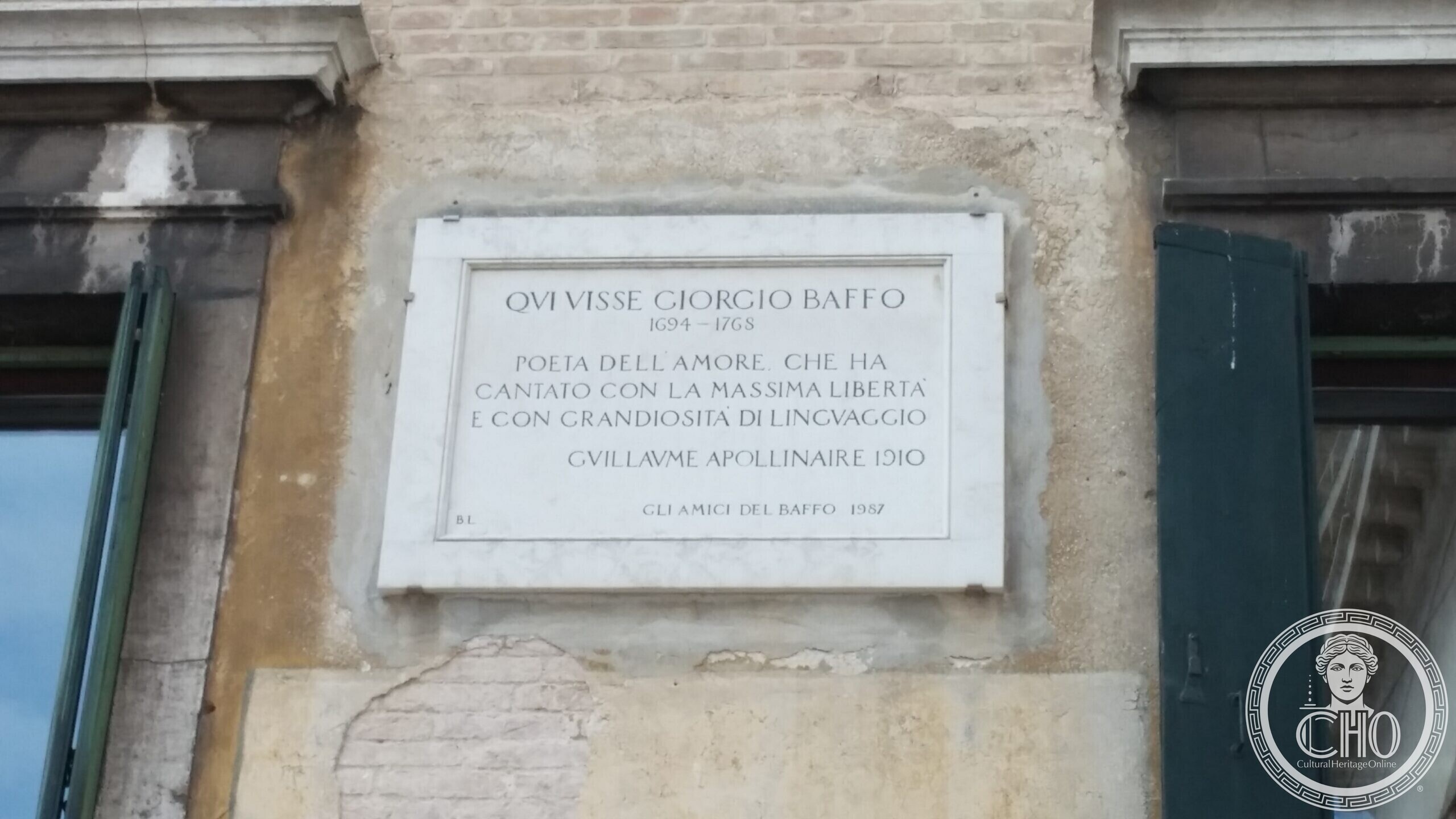 The carved stone base of the flagpole on Campo San Maurizio in Venice, with the church behind it