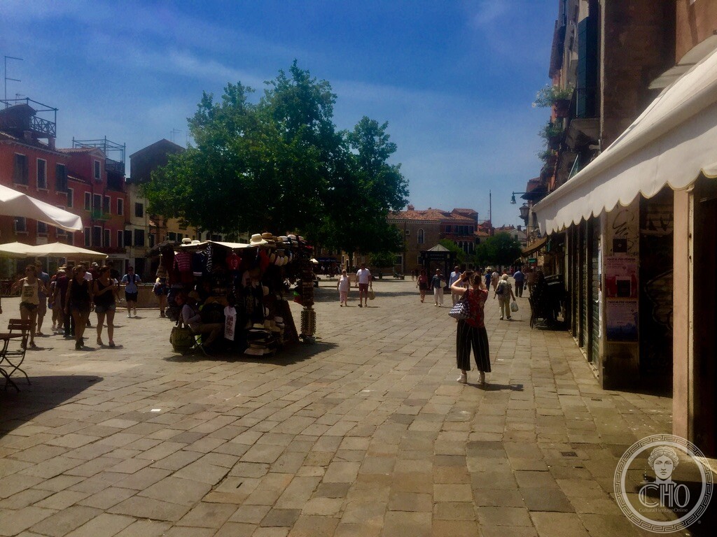 Wide view across the sunlit expanse of Campo Santa Margherita in Dorsoduro showing kiosks and café awnings