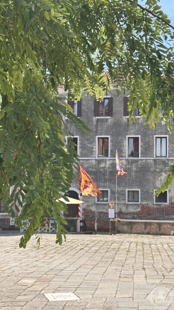 Detail view of a stone palace facade with Venetian flags on the edge of Campo Sant'Angelo