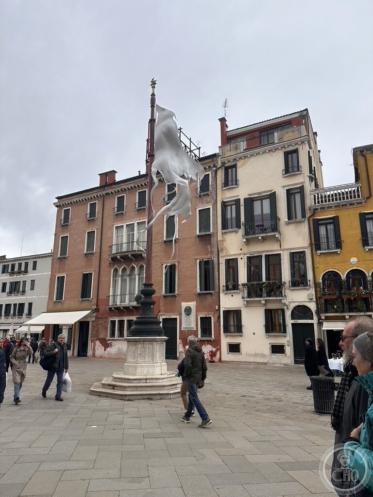 Open view across Campo Santo Stefano in Venice showing the central flagpole with contemporary sculpture installation and historic palazzi