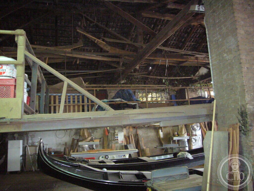 Black gondolas stored inside the timber-roofed workshop of Cantiere Crea