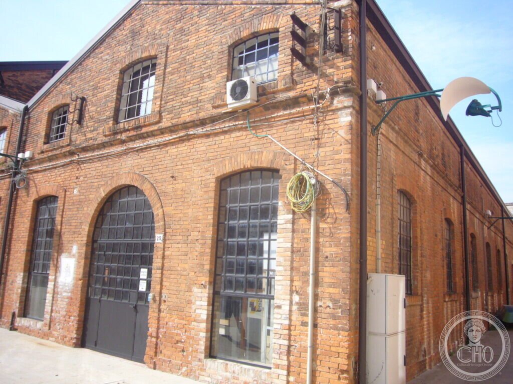 Corner of the brick workshop buildings of the former CNOMV shipyard on the Giudecca, with arched iron-framed windows
