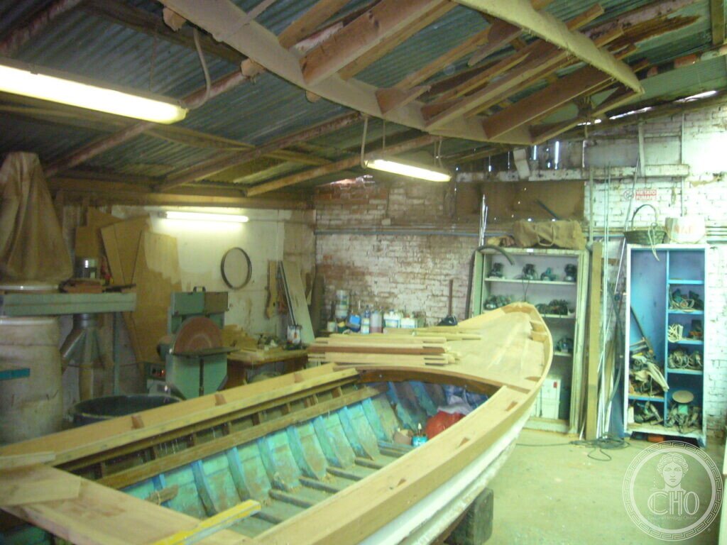 Venetian wooden boat under restoration with old blue framing and new timber gunwales in the Cantiere Crea workshop