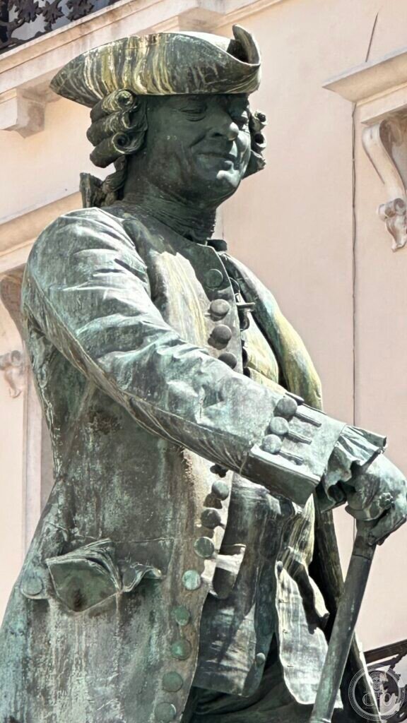 Close view of the head of the statue, tricorne hat and the modelled face, green with patina