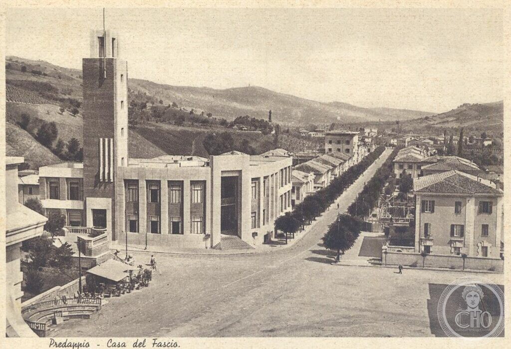 A period postcard of the Casa del Fascio in Predappio, the tall tower and the long front at the head of a tree-lined avenue, the hills behind