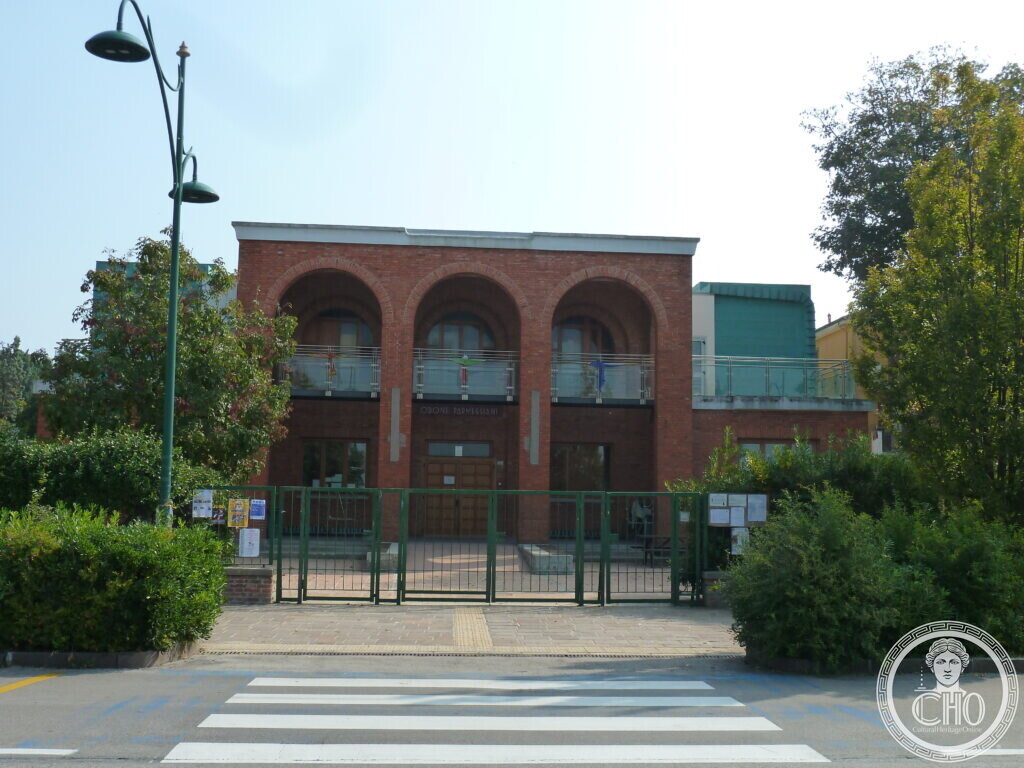 The building seen from the street, with the ODONE PARMEGGIANI sign over the entrance