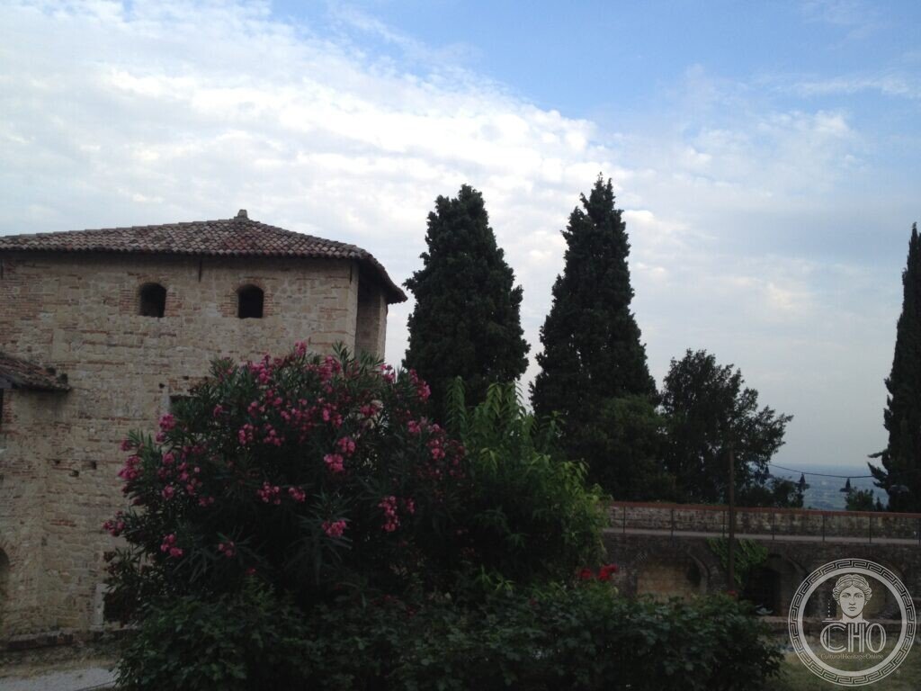 Medieval stone tower of the Castle of Asolo with flowering oleander in the foreground and the plain beyond