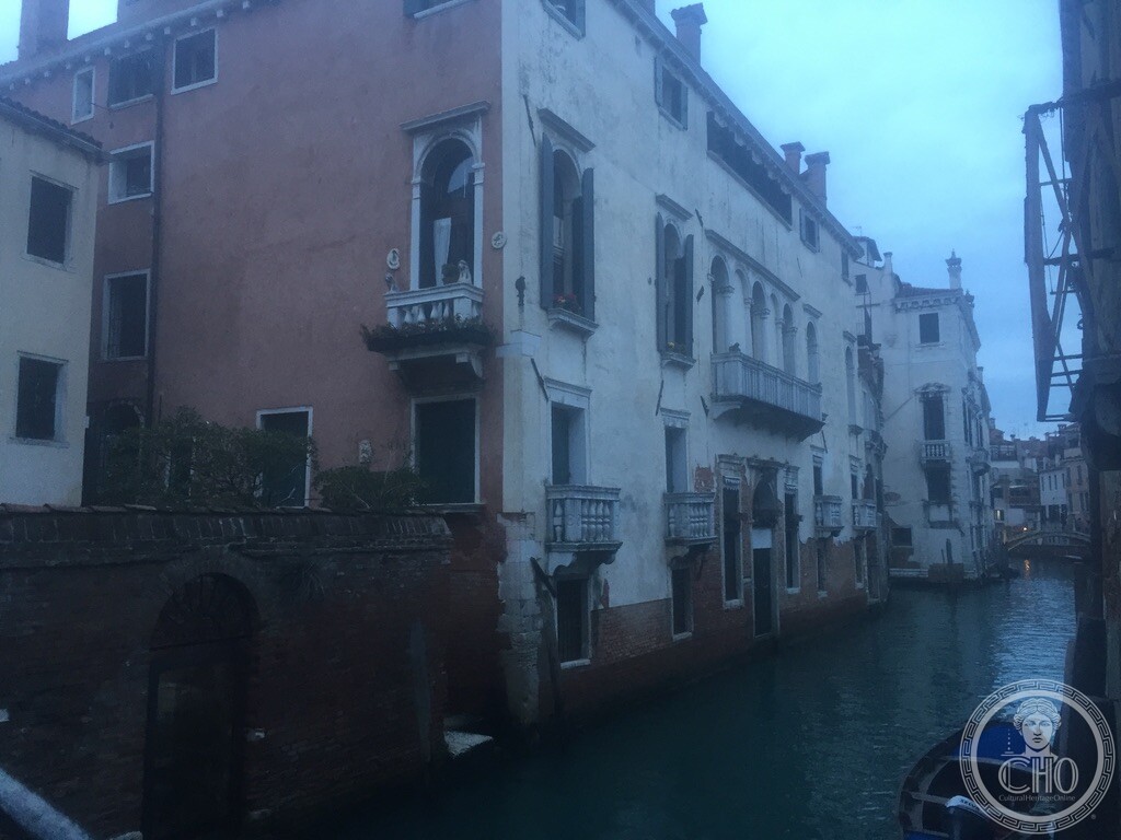 Twilight atmospheric view along a tranquil canal in Castello Venice with Gothic arched windows and balustrade balconies reflected in water