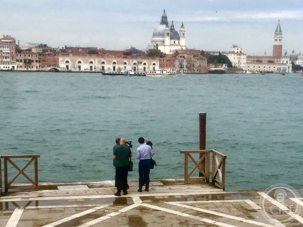 Documentary film crew on the wooden landing stage of Chiesa del Redentore overlooking the Giudecca Canal with Santa Maria della Salute and San Marco campanile
