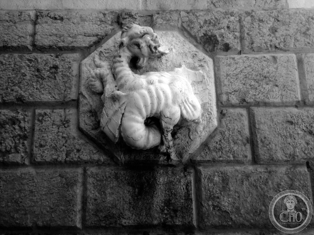 Carved stone octagonal relief depicting the legendary dragon of Saint Margaret on the church wall in Campo Santa Margherita