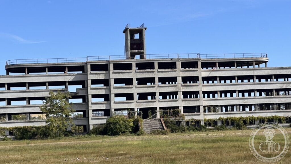 Five floors of concrete frames with a tall stair tower rising above the roof terrace