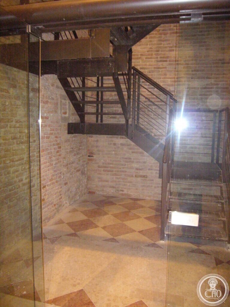 Metal staircase behind glass against the medieval brick wall of the former church