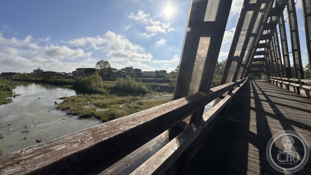 The timber deck and handrail of the footbridge running into the distance inside its steel frame