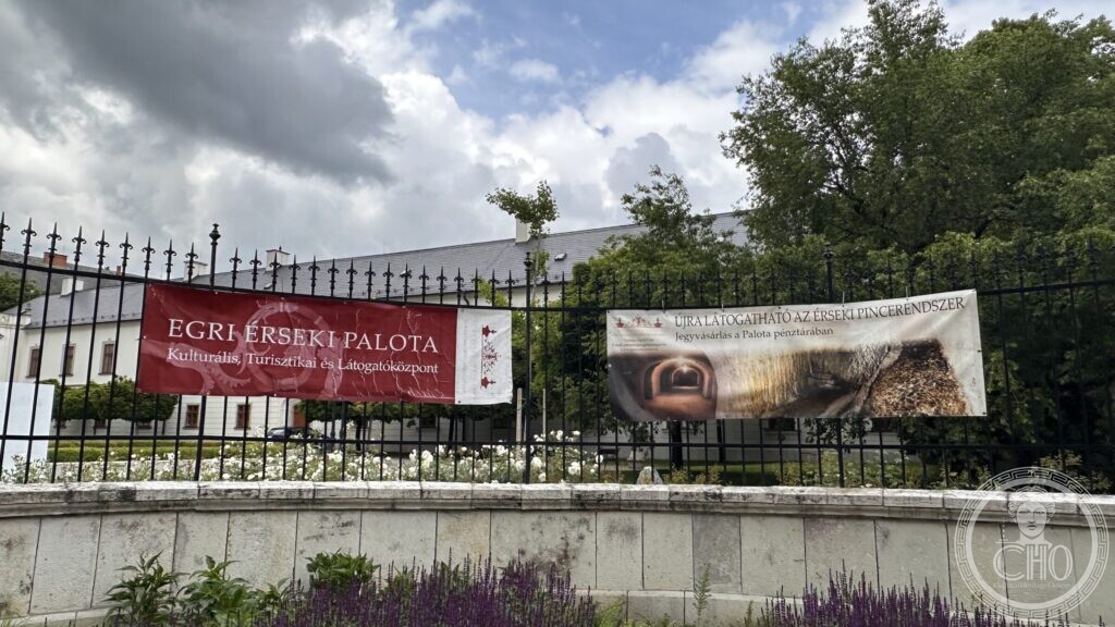 Two banners on the railing of the Archbishop's Palace in Eger: one naming the visitor centre, the other announcing that the archiepiscopal cellars are open again