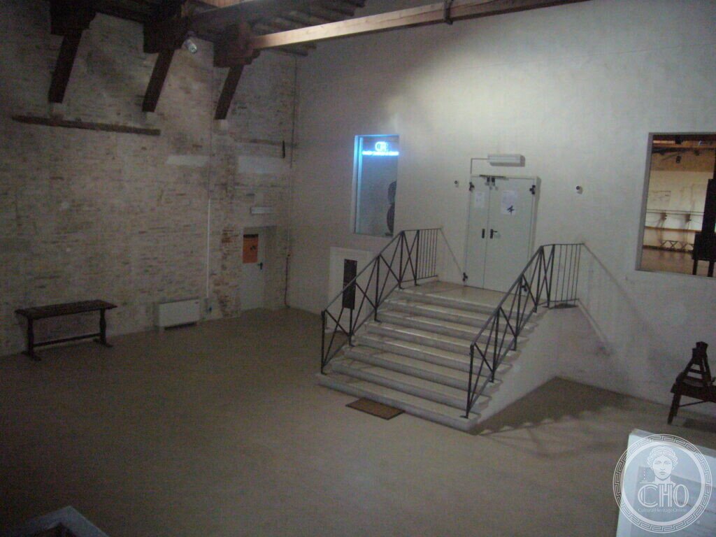 Interior of the former convent with exposed brick wall, timber beams and a modern staircase