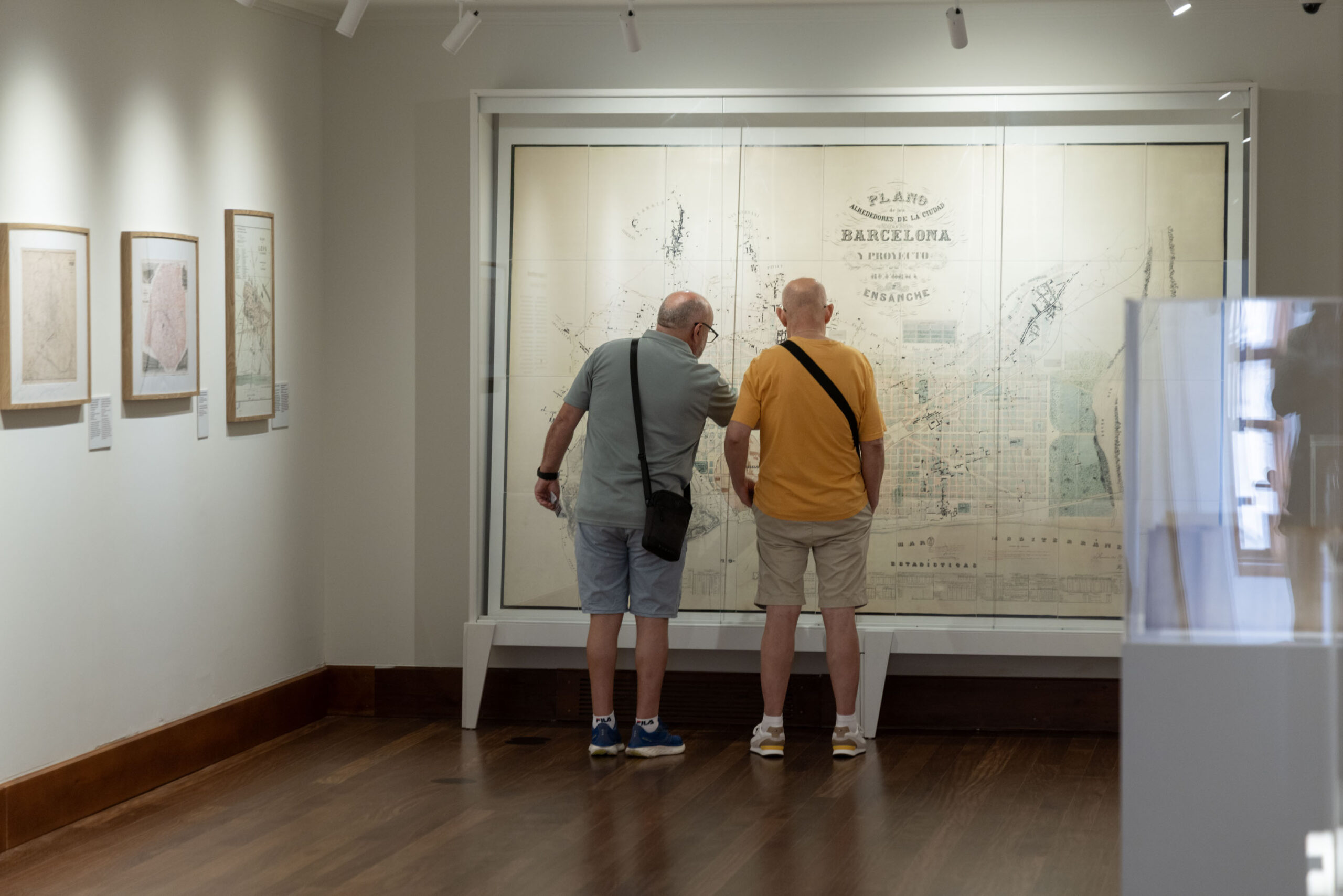 Visitors examine a large nineteenth-century plan of Barcelona and its Eixample extension in a display case