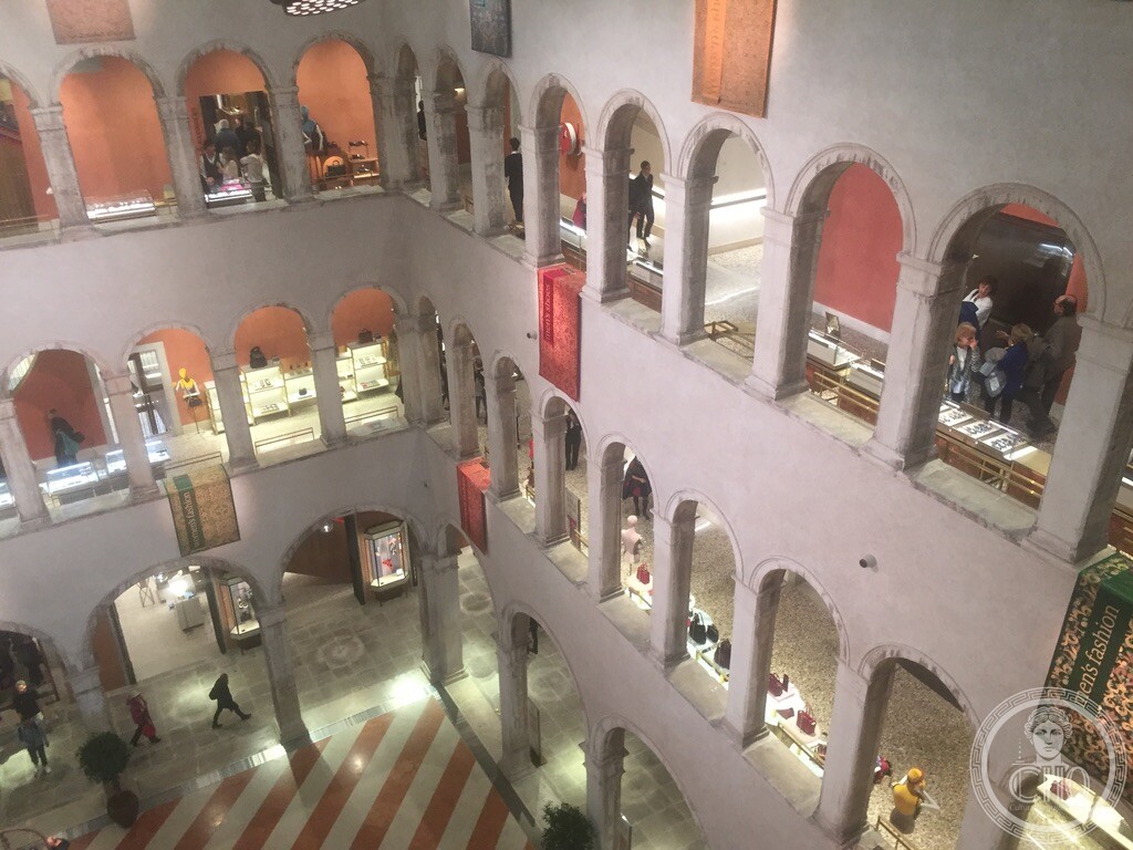 Arcaded upper galleries around the Fondaco dei Tedeschi's inner courtyard, with shop displays