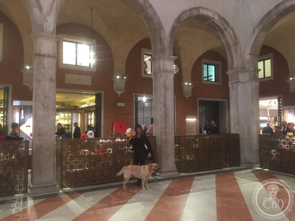 Interior arcade of the Fondaco dei Tedeschi with shoppers and a dog, when it was still open as a DFS store