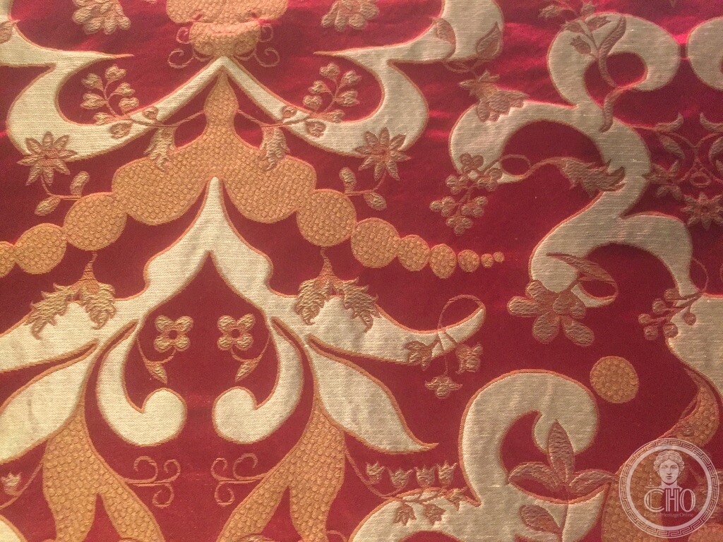 Close-up of a red and gold brocade textile on display inside the Fondaco dei Tedeschi