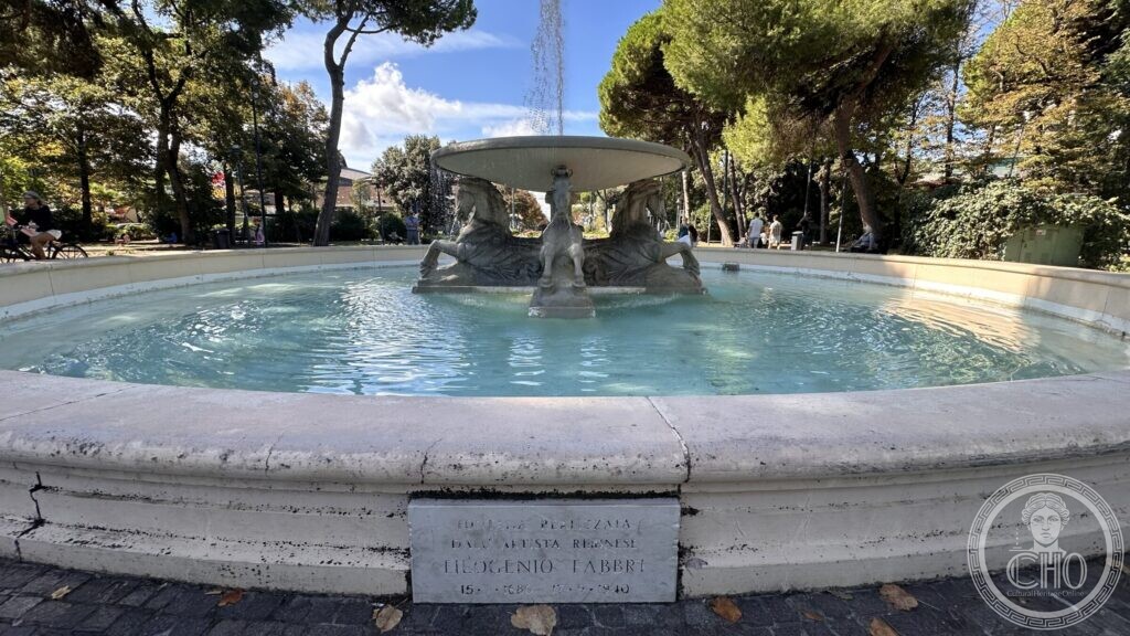 The whole circular basin of the fountain with the marble plaque set into its rim in the foreground