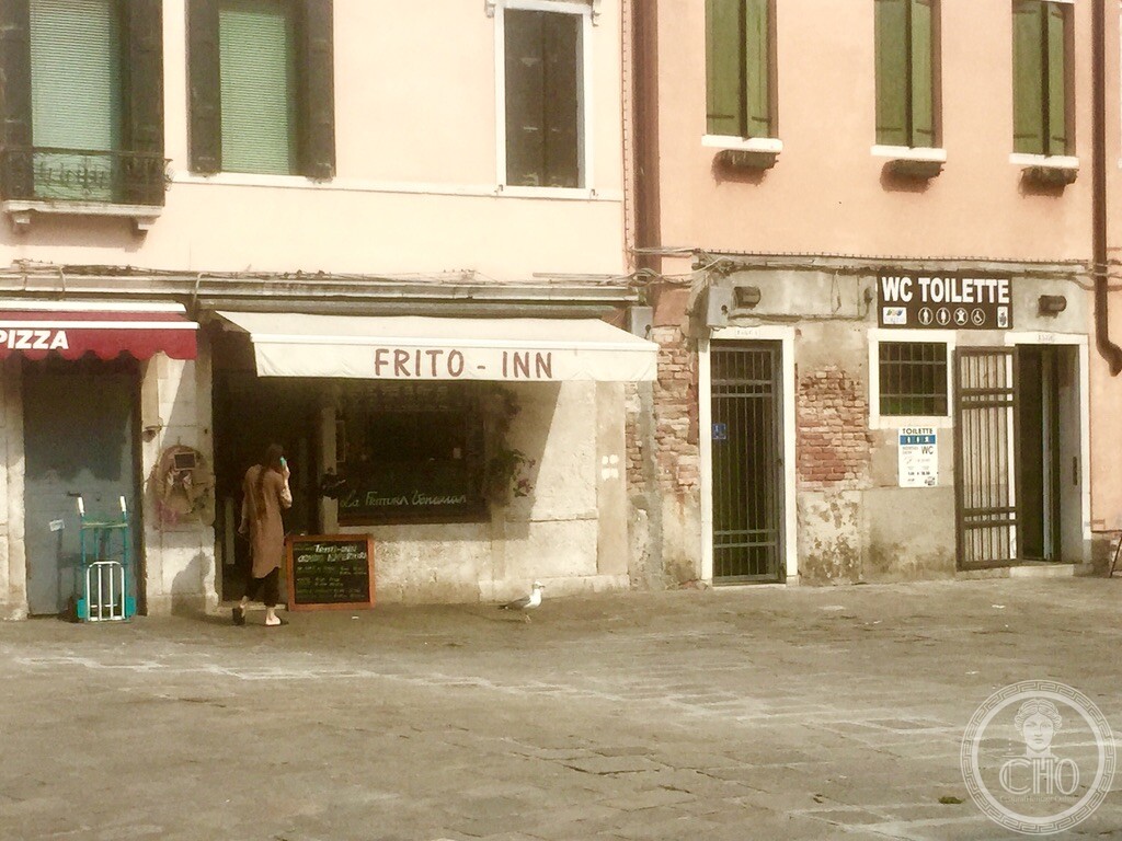 Close up view of the traditional Venetian fried seafood shop Frito-Inn with patrons and seagull on Campo San Leonardo in Venice